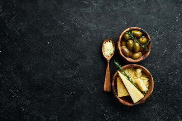 Dairy products. Parmesan cheese, olives and snacks on a stone table. Top view. On a concrete background.
