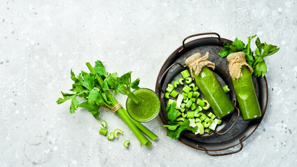 Green celery stalk and celery juice on gray stone background. Vegetarian drink. Free space for text.