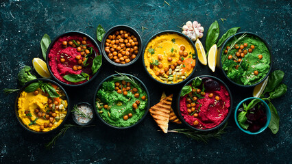 Colorful hummus bowls. Flat-lay of various vegetarian dips hummus. On a concrete black background.