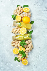 Homemade lemonade with ginger, lemon and mint on a wooden board. Vitamin Healthy Drink Concept. On a stone background.