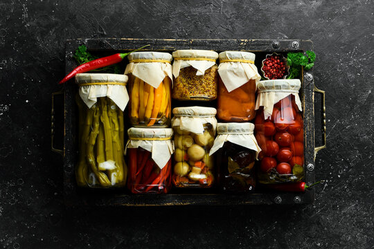 Jars of tasty pickled vegetables in a box. Food stocks in case of crisis. On a stone background. Top view.