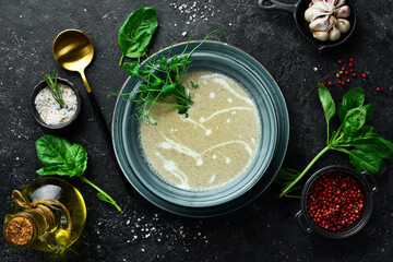 Mushroom cream soup with cream and conjut. In a blue plate. On a black stone background.