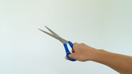 Open scissors in right hand on white background