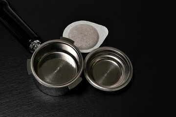 portafilter for brewing espresso coffee under pressure and Coffee Pod Capsule for Italian Espresso Machine. Black slate background.
