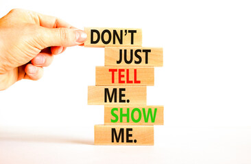Tell or show symbol. Concept words Do not just tell me, show me on wooden blocks. Beautiful white table white background. Businessman hand. Business tell or show concept. Copy space.