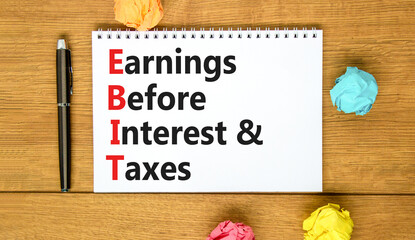 EBIT symbol. Concept words EBIT earnings before interest and taxes on white note on beautiful wooden background. Business EBIT earnings before interest and taxes concept. Copy space.