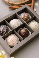 Sweet gift closeup. Chocolate candies in dark box. Cheese truffles on gray background. Set of 6 candies