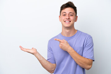 Young handsome Brazilian man isolated on white background holding copyspace imaginary on the palm...