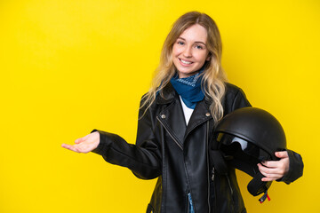 Blonde English young girl with a motorcycle helmet isolated on yellow background extending hands to the side for inviting to come