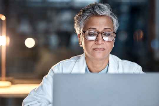 Woman, doctor and laptop in office at night at workplace, hospital or desk for medical career vision. Healthcare expert, dark clinic or focus for reading at computer, email or cancer research article