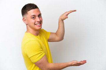 Young brazilian man isolated on white background holding copyspace to insert an ad