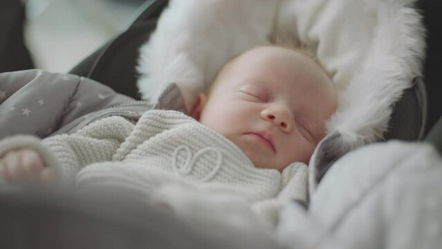 Close-up shot of a baby girl sleeping peacefully in warm clothes at home