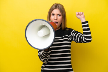 Young caucasian woman isolated on yellow background shouting through a megaphone to announce something