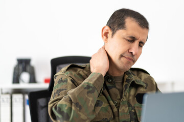 Shot of a mid adult male soldier experiencing discomfort in his shoulders while sitting at his desk