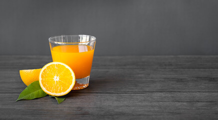 Orange juice in glass and fresh cut orange fruits   on dark wooden background
