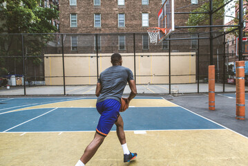 Athletic african american basketball player training on a court in New York - Sportive man playing...