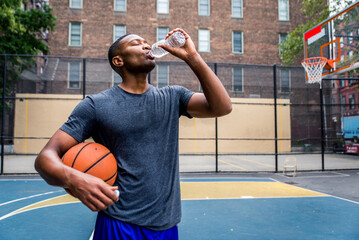 Athletic african american basketball player training on a court in New York - Sportive man playing basket outdoors