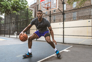 Athletic african american basketball player training on a court in New York - Sportive man playing basket outdoors