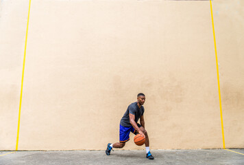 Athletic african american basketball player training on a court in New York - Sportive man playing...