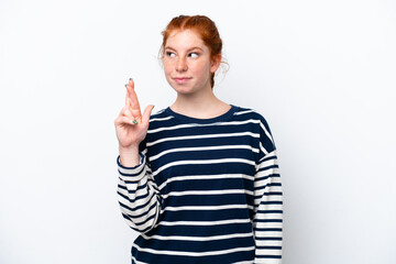 Young reddish woman isolated on white background with fingers crossing and wishing the best
