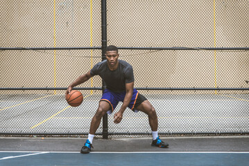 Athletic african american basketball player training on a court in New York - Sportive man playing...