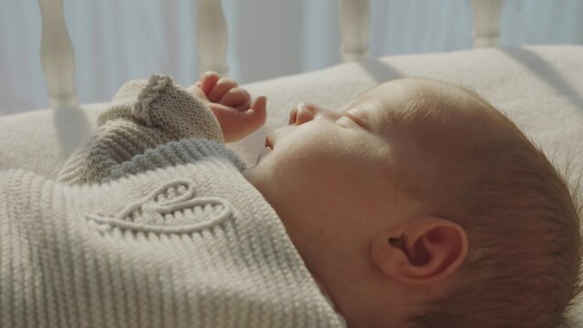 Close-up shot of a adorable baby sleeping and dreaming peacefully in a crib. Indoor shot with sun light on the child face