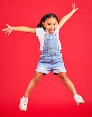 Excited, playful and portrait of a girl jumping while isolated on a red background in a studio....