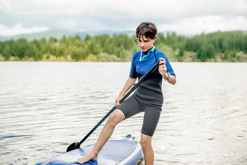 active teen girl paddling a sup board on a river or lake, natural background, active healthy sporty lifestyle