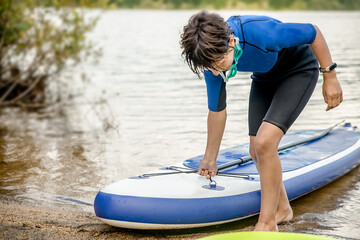active teen girl paddling a sup board on a river or lake, natural background, active healthy sporty lifestyle