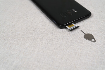 Sim ejector tool and SIM card slot of smartphone on fabric background