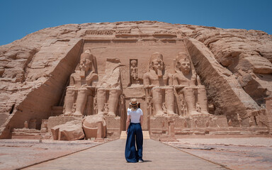 Young girl on her back enjoying the temple of Abu Simbel on her trip through Egypt - obrazy, fototapety, plakaty
