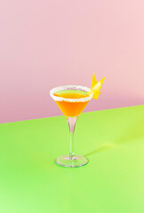 Sidecar alcoholic cocktail with cognac, liqueur, lemon juice and ice. Pink and green pop background