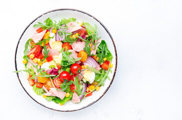 Fish tuna and fresh vegetables salad with cherry tomatoes, red onion, eggs, corn, paprika, lettuce, radicchio and arugula. White table background, top view