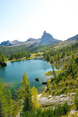 Aussicht auf türkisen See und grünen Wald mit Felsmassiv in den Dolomiten.