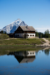Fototapeta na wymiar Hütte am See mit Gipfel und Schnee im Hintergrund in den Dolomiten bei Cortina.
