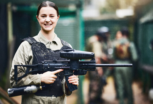 Paintball, happy and portrait of woman with gun in safety uniform for outdoor shooting game with smile. Excited tournament girl in vest protection ready for shooter sport and activity.