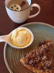 Apple Crumble Dessert with vanilla ice cream on Rustic Wooden Surface