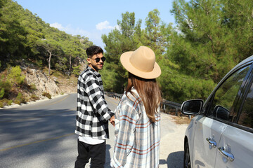 Young couple wearing casual clothing walking down the switchback road, left their car parked on the...