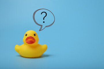 Yellow toy duck with question mark isolated on a blue background.