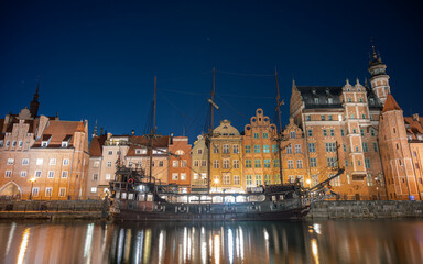 Night image of the river and the buildings of the city of Gdansk (Poland) illuminated, capturing the reflection of the water with a medieval ship.