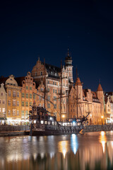 Fototapeta na wymiar Night image of the river and the buildings of the city of Gdansk (Poland) illuminated, capturing the reflection of the water with a medieval ship.