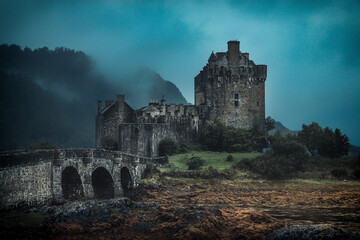 Fototapeta premium Eilean Donan Castle with dark clouds and fogs in gloomy days