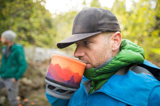 Mountaineer sips tea out of a pot at basecamp.