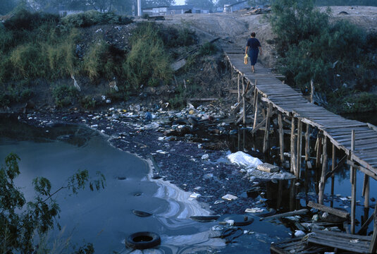 A woman crossing a wastewater canal in Matamoras, Mexico, USA.