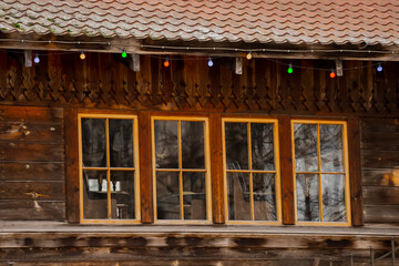 Festive colourful bulbs on old rustic wooden exterior house and wood tile windows