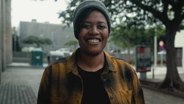Happy African woman smiling in front of a camera in the city