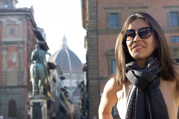 Fototapeta premium Portrait of woman smiling with sunglasses unfocused background at Florence, Italy. 50mm lens