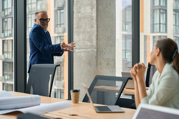 Experienced businessman using body language for communicating with colleague