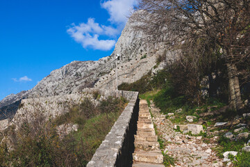Fototapeta na wymiar Kotor, Montenegro, process of climbing to the top of San Giovanni Fortress, Fort St. John, old medieval town, hiking on the Ladder of Kotor, sunny day with a blue sky and mount Lovcen and Orjen
