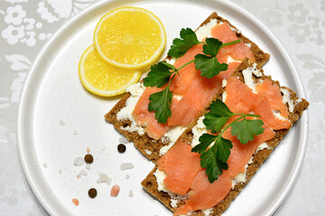 healthy snack with crisp bread, salmon slices and ricotta cheese isolated on white tray, macro